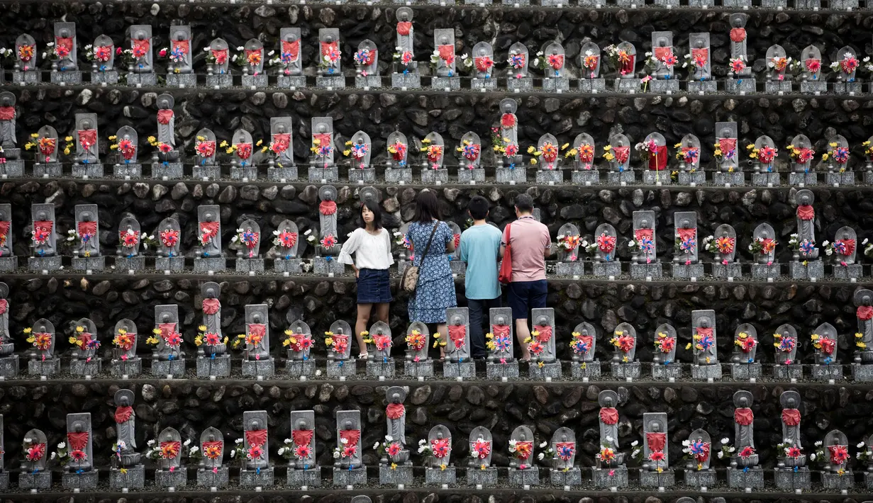 Warga berdoa di patung Jizo yang berdiri di Kuil Buddha Jizoji, Oganomachi, Prefektur Saitama, Jepang, Senin (13/8). Tanggal 13 Agustus diyakini sebagai salah satu di mana jiwa-jiwa orang mati kembali ke dunia di bawah ajaran Buddha. (Behrouz Mehri/AFP)