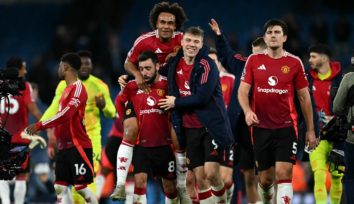 Pemain Manchester United, Bruno Fernandes (kedua kiri) bersama Joshua Zirkzee (tengah) dan Rasmus Hojlund (kedua kanan) melakukan selebrasi usai pertandingan sepak bola Liga Premier Inggris melawan Manchester City di Stadion Etihad, Manchester, Inggris, pada 15 Desember 2024. (Paul ELLIS/AFP)