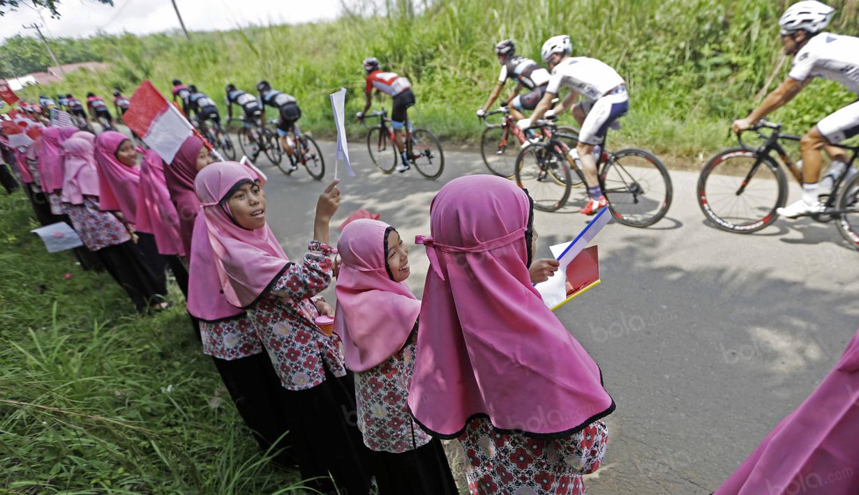 Anak-anak sekolah Dharmasraya memberikan semangat untuk para pebalap saat Tour de Singkarak 2016 dari Sinjunjung menuju Dharmasraya, Sumatera Barat, Jumat (12/8/2016). (Bola.com/Nicklas Hanoatubun)