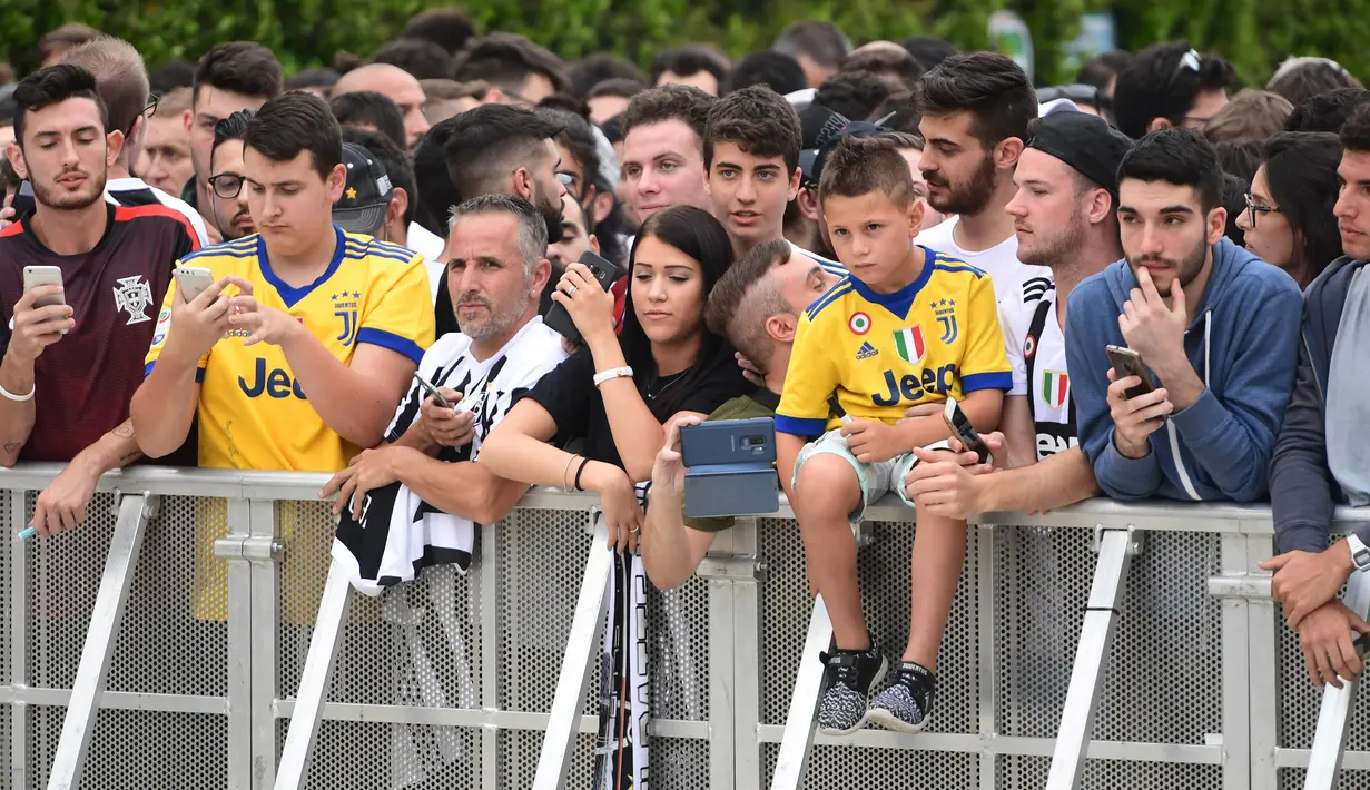 Suporter Juventus bersiap menyambut kedatangan pemain baru Juventus Cristiano Ronaldo untuk menjalani tes medis di pusat layanan kesehatan Juventus (J-Medical) di Turin, Italia, (16/7). (AFP Photo/Miguel Medina)