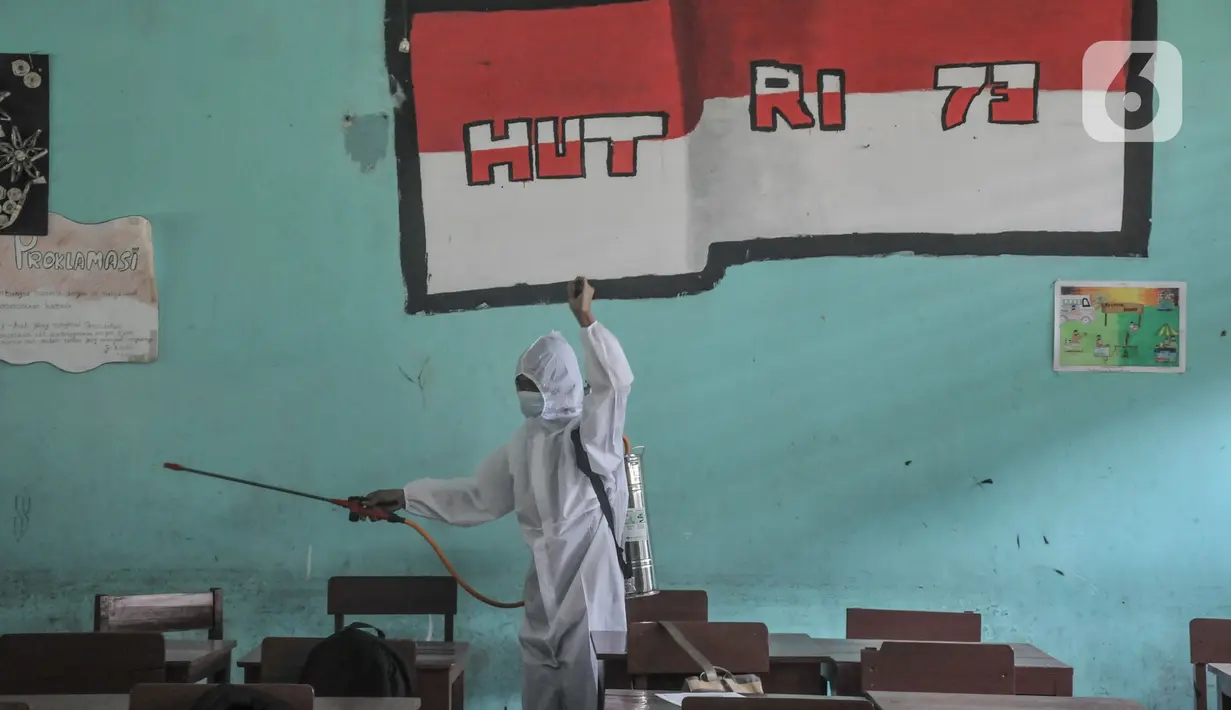 Petugas sekolah menyemprotkan disinfektan di salah satu ruang kelas usai Pembelajaran Tatap Muka (PTM) 100 persen di SMP Negeri 9 Depok, Senin (24/1/2022). Penyemprotan disinfektan juga guna mengantisipasi penyebaran Covid-19 varian Omicron yang terus meningkat. (merdeka.com/Iqbal S Nugroho)
