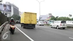 Pengendara motor melintas melawan arus jalan tol arah Merak dari persimpangan Taman Anggrek, Jakarta (4/2). Minimnya rambu-rambu lalulintas jalan menuju tol Merak membuat pengendara motor tidak mengetahuinya. (Liputan6.com/Helmi Afandi)