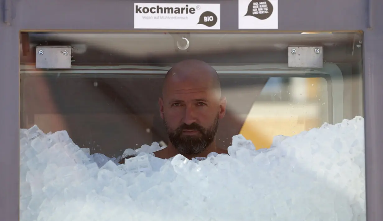 Perenang es Austria Josef Koeberl berdiri dalam kabin kaca berisi es di Melk, Austria, Sabtu (5/9/2020). Josef Koeberl berhasil memecahkan rekor dunia dengan berendam dalam es selama 2 jam, 30 menit, dan 57 detik. (AP Photo/Ronald Zak)