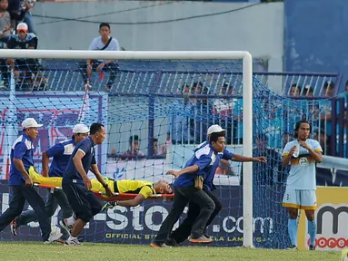 Kiper Persela Lamongan Choirul Huda dibawa oleh tim medis usai mengalami benturan dengan rekan setim, Ramon Rodrigues saat pertandingan Liga 1 di stadion Surajaya, Lamongan (15/10). (AFP Photo/Juni Kriswanto)