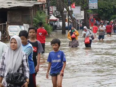 Warga melintasi banjir yang menggenangi Jalan KH Hasyim Ashari, Tangerang, Banten, Kamis (2/1/2020). Banjir yang menggenangi jalan penghubung Jakarta- Tangerang tersebut mulai surut dan sudah bisa dilintasi pejalan kaki. (Liputan6.com/Angga Yuniar)