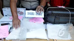 Petugas menunjukan barang bukti jenis shabu saat merilis barang bukti di Polsek Senen, Jakarta, Senin (6/4/2015). Polisi berhasil mengamankan 2 kg shabu dari warga kenegaraan Iran, Hajinasiri Mohsen Aliasgharr. (Liputan6.com/Johan Tallo)