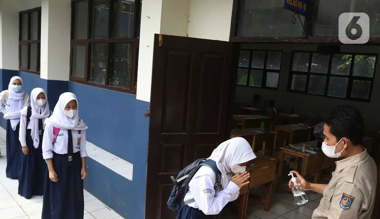 Siswi memberi salam kepada guru sebelum mengikuti Pembelajaran Tatap Muka Terbatas (PTMT) di SMPN 1 Depok, Depok, Jawa Barat, Senin (4/10/2021). PTMT diberlakukan dengan protokol kesehatan dan pembelajaran hanya dilakukan seminggu dua kali selama dua jam. (Liputan6.com/Herman Zakharia)