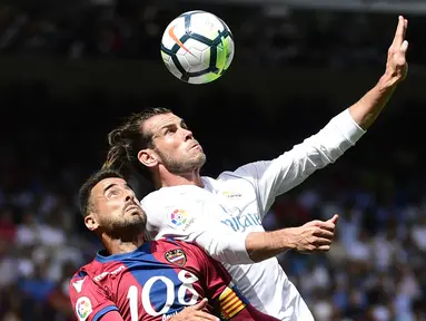 Pemain Levante, Pedro Lopez (kiri) berebut bola dengan pemain Real Madrid, Gareth Bale pada lanjutan La Liga di Santiago Bernabeu stadium, Madrid (9/9/2017). Madrid bermain imbang 1-1. (AFP/Pierre-Philippe Marcou)