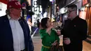 Seorang wanita memberikan uang 1.000 yen untuk berswafoto dengan peniru pemimpin Korea Utara Kim Jong-un dan peniru Presiden AS, Donald Trump selama KTT G20 di Osaka, Jepang, Jumat (28/6/2019). Sejumlah pemimpin dunia berkumpul dalam KTT G20 yang berlangsung dua hari di Osaka (Charly TRIBALLEAU/AFP)
