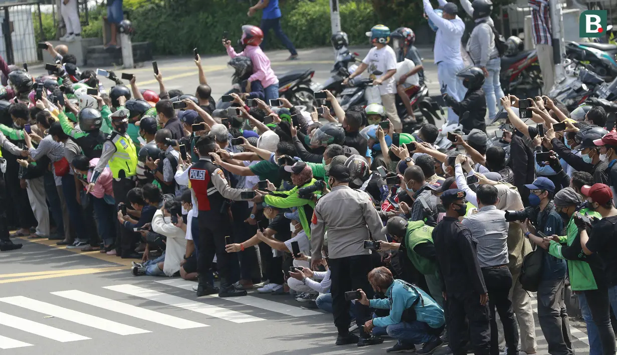 Warga saat melihat parade pembalap MotoGP di depan Sarinah Thamrin, Jakarta Pusat. Sebanyak 20 pembalap melakukan parade motor dari Istana Merdeka menuju Hotel Kempinski di Bundaran HI Jakarta Pusat, Rabu (16/03/2022). (Bola.com/M Iqbal Ichsan)
