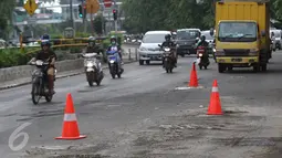 Kendaraan melintasi jalanan yang berlubang di Jalan Otista Raya, Jakarta, Rabu (22/2). Kondisi tersebut berbahaya bagi pengguna jalan, khususnya pengendara sepeda motor yang melintas saat malam hari. (Liputan6.com/Immanuel Antonius)