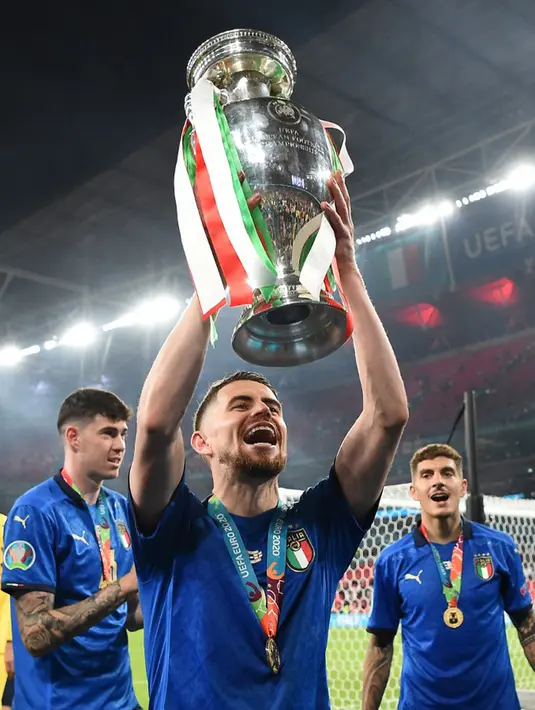 Pemain Italia Jorginho berpose dengan trofi juara Euro 2020 usai mengalahkan Inggris pada pertandingan final di Stadion Wembley, London, Inggris, 11 Juli 2021. Gelandang tengah ini layak masuk nominasi Ballon d'Or karena memberi pengaruh bagi Italia dan Chelsea saat juara. (Andy Rain/POOL/AFP)
