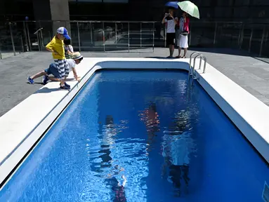 Pengunjung melihat karya seni Swimming Pool dalam sebuah pameran bertajuk "The Confines of the Great Void" di Museum CAFA, Beijing, 23 Juli 2019. Karya seni buatan seniman Argentina, Leandro Erlich ini tampak seperti kolam renang pada umumnya yang penuh dengan air. (WANG Zhao/AFP)