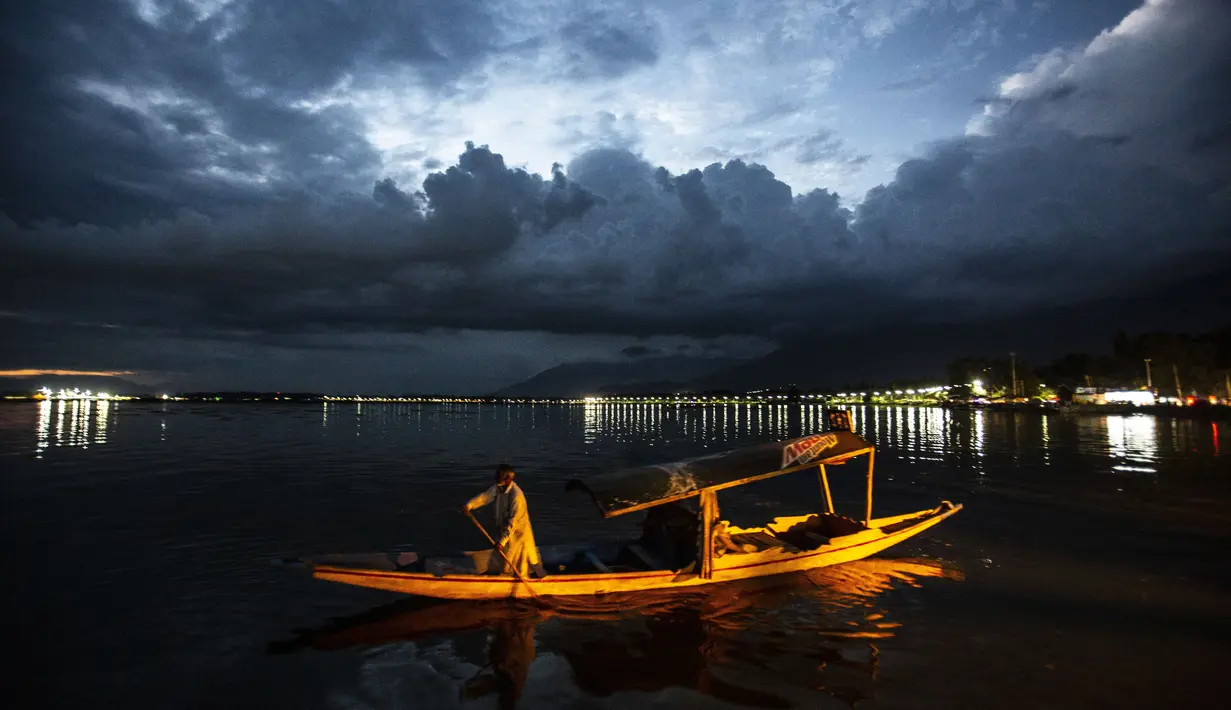 Seorang tukang perahu Kashmir kembali di tepi danau Dal setelah bekerja seharian, di Srinagar, Kashmir yang dikuasai India, Minggu (1/8/2021). Danau terbesar kedua di propinsi Jammu dan Kashmir ini merupakan pusat pariwisata dan rekreasi. (AP Photo/Mukhtar Khan)