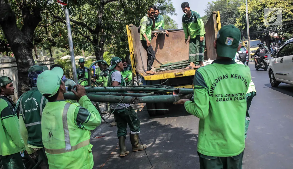 Petugas Suku Dinas Kehutanan Jakarta Pusat mengangkut pagar yang dirusak pengunjuk rasa ke dalam truk usai demonstrasi di depan TPU Karet, Jakarta, Selasa (1/10/2019). Pengerusakan dilakukan pengunjuk rasa saat terlibat bentrok dengan polisi di kawasan tersebut. (Liputan6.com/Faizal Fanani)