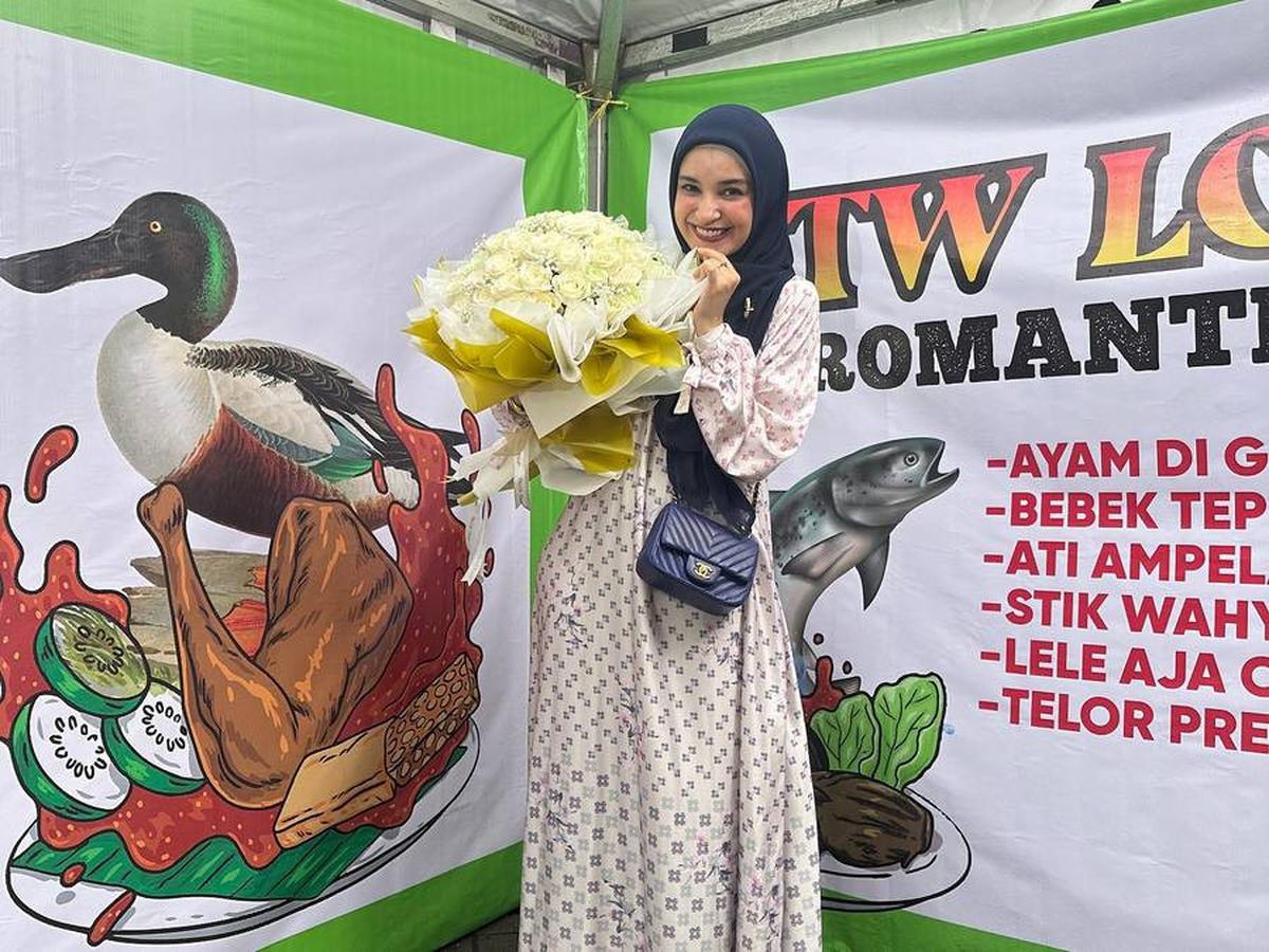 Shireen tersenyum manis saat berpose dengan buket bunga dari Wisnu. Pesona ibu tiga anak ini memancar dalam senyuman dan kebahagiaannya.