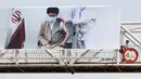 Seorang pria melintasi jembatan di mana spanduk yang menunjukkan pemimpin tertinggi Iran Ayatollah Ali Khamenei menerima vaksin COVID-19, di Teheran, Sabtu (3/7/2021). Presiden Hassan Rouhani mengaku khawatir Iran akan dilanda gelombang kelima akibat mewabahnya varian Delta. (ATTA KENARE/AFP)