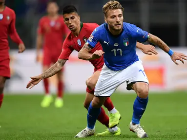 Striker Italia, Ciro Immobile membawa bola dari kawalan bek Portugal, Joao Cancelo selama pertandingan UEFA Nations League di Stadion San Siro di Milan (17/11). Italia bermain imbang 0-0 atas Portugal. (AFP Photo/Marco Bertorello)