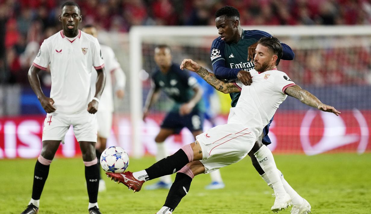 Pemain Sevilla, Sergio Ramos, berusaha menendang bola saat duel dengan pemain Arsenal, Eddie Nketiah, pada laga Liga Champions di Stadion Ramon Sanchez Pizjuan, Rabu (25/10/2023). Bek veteran asal Spanyol ini nampak tak sekuat saat muda dulu. (AP Photo/Jose Breton)