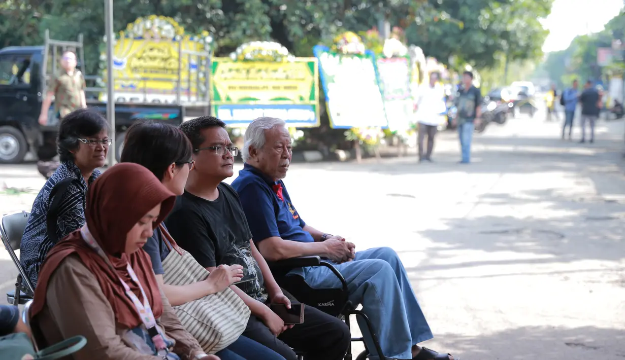 Suasana sedih nampak terlihat dari saudara-saudara Mike Mohede yang nampak duduk. Terlihat juga sepanjang jalan karangan bunga berjejer dipinggir jalan. (Adrian Putra/Bintang.com)