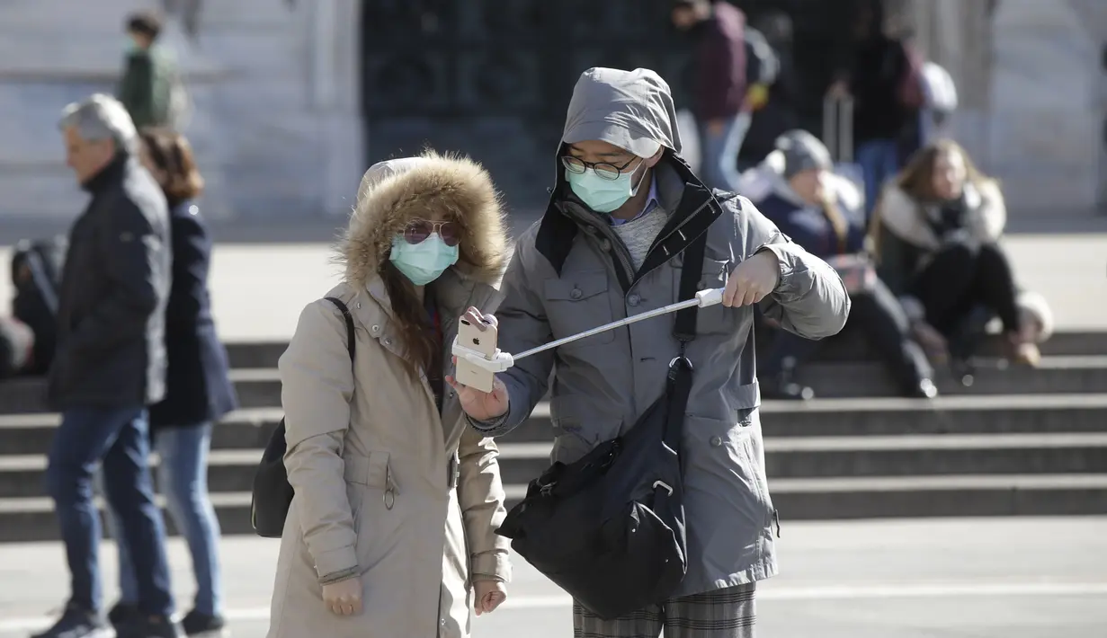Suami istri bersiap selfie di kota Duomo, Milan, Italia, Kamis (27/2/2020). Kementerian Kesehatan Italia, hingga Rabu 4 Maret, mencatat ada 3.089 orang yang terinfeksi Virus Corona COVID-19. Rinciannya, 2.706 kasus positif, 107 orang meninggal dunia, dan 276 orang sembuh. (AP Photo/Luca Bruno)