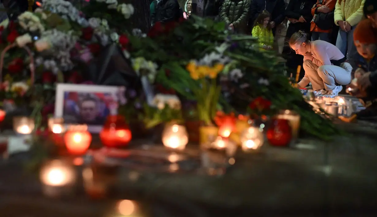 Masyarakat berkumpul di sebuah tugu peringatan darurat dengan bunga dan lilin yang diletakkan sebagai penghormatan kepada mendiang pemimpin oposisi Rusia Alexei Navalny di depan Kedutaan Besar Rusia di Beograd, pada 1 Maret 2024. (OLIVER BUNIC/AFP)