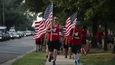 Sejumlah warga yang tergabung dalam kelompok veteran berlari sambil membawa bendera Amerika Serikat untuk menunjukan solidaritas terkait penembakan di Virginia, AS (14/6). (Alex Wong/Getty Images/AFP)