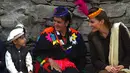 Duchess of Cambridge, Kate Middleton mengenakan topi tradisional suku Kalash berbincang dengan seorang anak suku Kalash selama kunjungannya ke Lembah Bumburate di Distrik Chitral utara Pakistan (16/10/2019). (AFP Photo/Farooq Naeem)