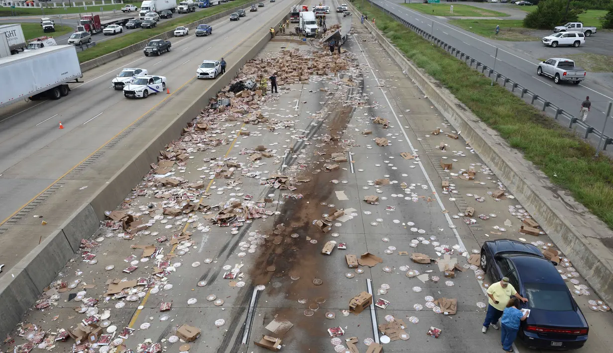 Ratusan pizza beku berserakan di Jalan Raya Arkansas, Amerika Serikat, 9 Agustus 2017. Kejadian disebabkan truk pembawa pizza beku dengan 18 roda kehilangan kendali setelah melintasi jembatan dan terbalik. (Arkansas Department of Transportation via AP)