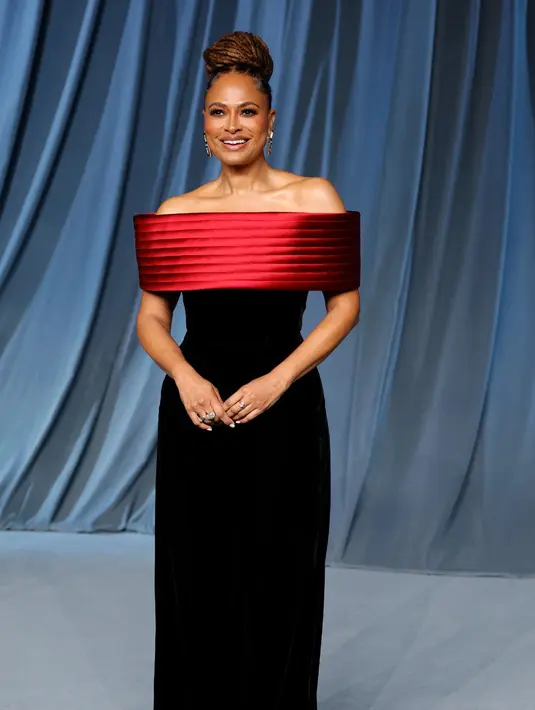 Ava DuVernay mengenakan gaun kolom off-shoulder berbahan beludru hitam dengan detail garis leher satin berwarna burgundy. [Dok/Louis Vuitton].