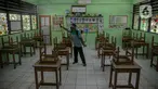 Seorang guru mendisinfeksi kelas yang akan digunakan di SDN Kenari 08, Jakarta, Selasa (6/4/2021). Pemerintah Provinsi DKI Jakarta akan melakukan uji coba pembelajaran tatap muka terbatas di 100 sekolah mulai 7 April hingga 29 April 2021. (Liputan6.com/Faizal Fanani)