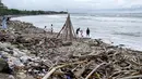 Orang-orang terlihat di samping tumpukan puing-puing dan sampah di di Pantai Kuta, Kabupaten Badung, Bali pada 26 Desember 2024. (SONNY TUMBELAKA/AFP)