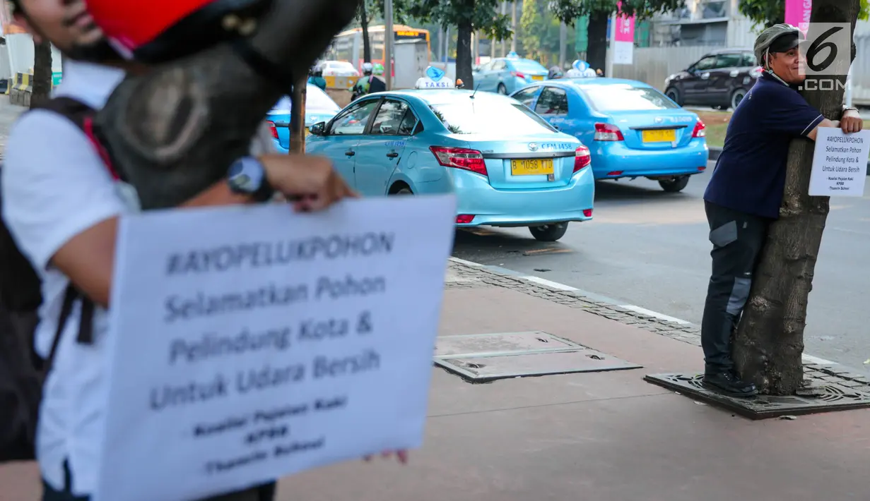 Ekspresi pria yang memeluk pohon saat menggelar aksi #ayopelukpohonini di Jalan Sudirman, Jakarta, Jumat (22/9). Aksi tersebut itu bentuk penolakan terhadap rencana Pemprov DKI Jakarta yang akan memindahkan sekitar 3.000 pohon.(Liputan6.com/Faizal Fanani)