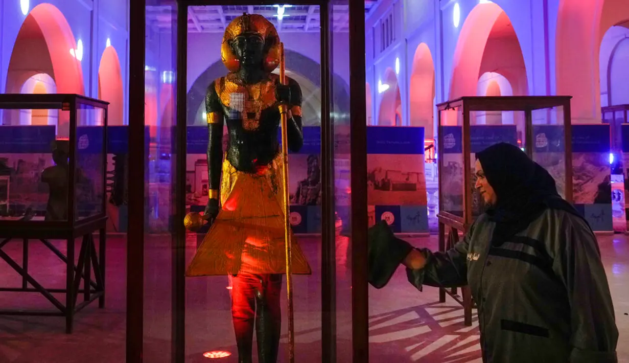 Seorang wanita membersihkan jendela patung kayu berhias roh Penjaga Kerajaan Raja Tutankhamun jelang perayaan untuk menghormati Hari Pariwisata Dunia dan peringatan 200 tahun Egyptology sebagai ilmu di Museum Mesir, Kairo, Mesir, 27 September 2022. (AP Photo/Amr Nabil)