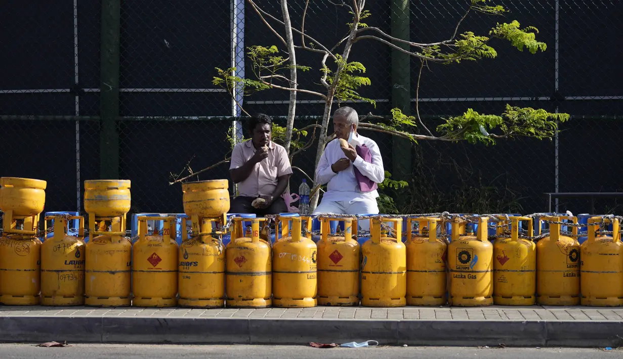 Orang-orang menyantap sarapan sambil duduk di dekat barisan tabung gas kosong yang ditempatkan di luar Galle International Cricket Stadium, di Galle, Sri Lanka, Selasa (28/6/2022). Selain persoalan gas dan BBM, masyarakat juga dihadapkan dengan harga barang kebutuhan pokok yang semakin mahal akibat nilai inflasi yang terus meningkat. (AP Photo/Eranga Jayawardena)