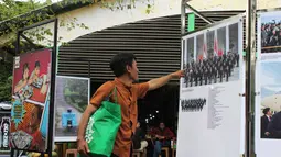 Pameran ini diselenggarakan dalam rangka memperingati satu tahun kepemimpinan Presiden Prabowo Subianto dan Wakil Presiden Gibran Rakabuming Raka. Tampak dalam foto, pengunjung menyaksikan karya foto jurnalistik dalam pameran Haluan Merah Putih Roadshow yang digelar di Selasar Kantin Taman Margasatwa Ragunan, Jakarta Selatan, Rabu (24/12/2025). (merdeka.com/magang/Rendi Saputra)