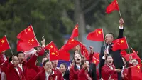 Atlet China mengibarkan bendera saat parade acara pembukaan Olimpiade 2024 di Paris, Sabtu (27/7/2024). (Steph Chambers/Pool Photo via AP)