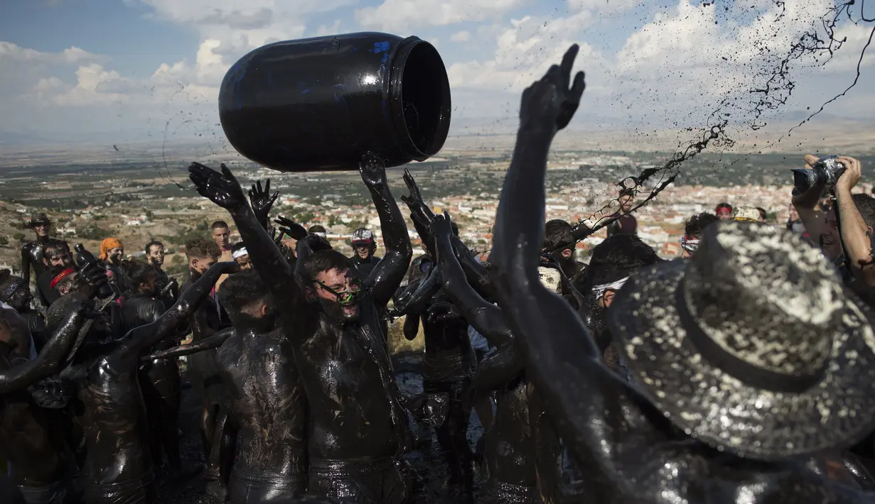 Peserta melemparkan ember berisi minyak hitam saat mengikuti Festival Tradisionlal Cascamorras di Baza, Granada, Spanyol (6/9/2019). Festival Cascamorras menggambarkan kekuatan dan kemampuan Baza untuk mempertahankan Virgen de la Piedad. (AFP Photo/Jorge Guerrero)
