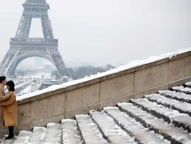 Pasangan berpose di depan Menara Eiffel di Paris, Prancis (7/2). Hujan salju yang sangat lebat membuat transportasi umum di paruh utara Prancis dan di Paris tidak dapat beroperasi. (AP Photo / Thibault Camus)