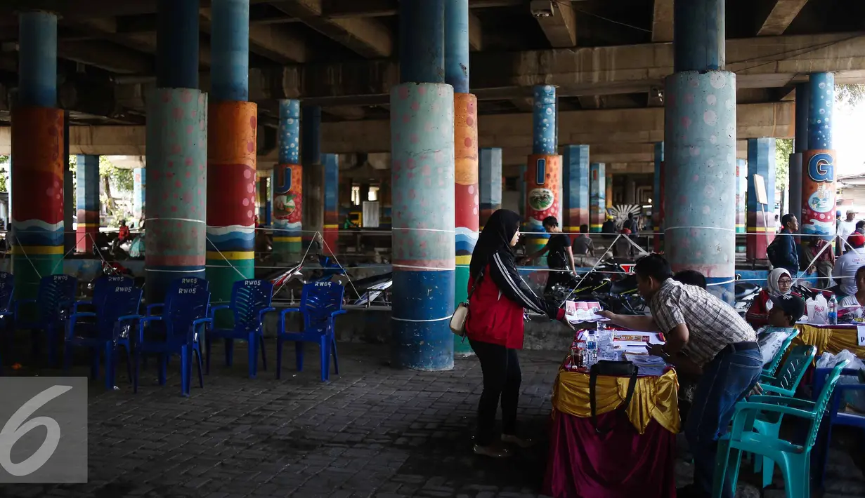 Panitia memberikan kertas suara di TPS 21 di bawah kolong jembatan tol akses Bandara, Petak Asem, Jakarta, Rabu (15/2). (Liputan6.com/Faizal Fanani)