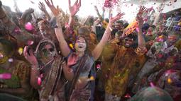 Umat Hindu bersorak saat bubuk berwarna dan air disemprotkan selama perayaan Festival Holi di kuil Kalupur Swaminarayan di Ahmedabad, India (18/3/2022).  Holi, festival warna Hindu, juga menandai datangnya musim semi. (AP Photo/Ajit Solanki)