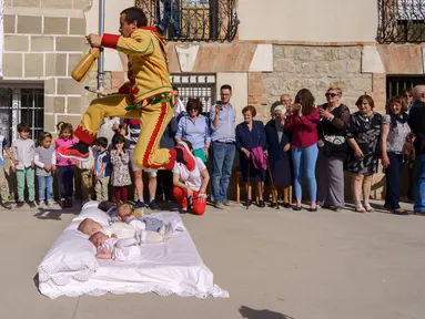 Pria berkostum setan melompati bayi-bayi yang diletakkan di atas matras selama tradisi El Salto del Colacho di desa Castrillo de Murcia, Spanyol, Minggu (3/6). Festival melompati bayi ini sudah menjadi perayaan tahunan sejak 1620 (afp/CESAR MANSO)