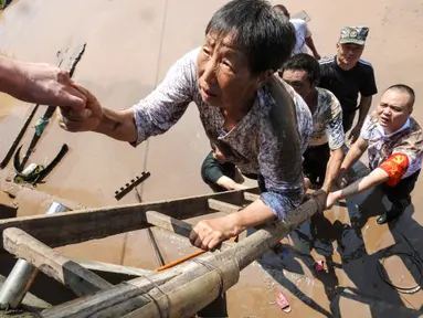 Pejabat desa mengevakuasi penduduk dari daerah banjir setelah hujan lebat di Dazhou di provinsi Sichuan barat daya China (12/7/2021). Banjir akibat hujan lebat melanda sejumlah wilayah di China. (AFP/STR)