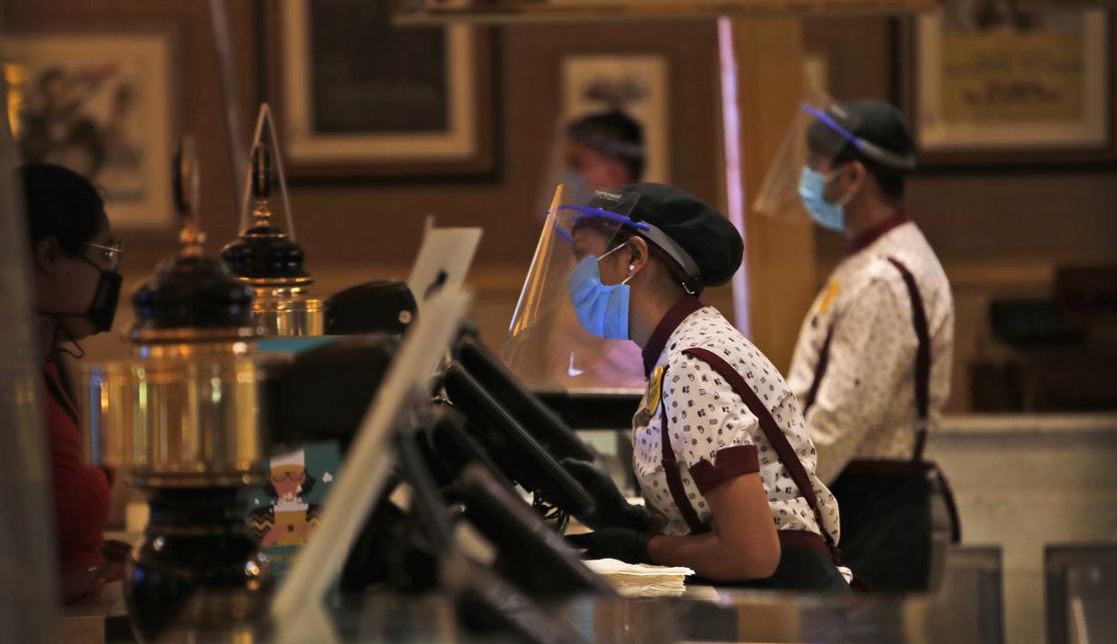 Karyawan bioskop PVR yang mengenakan pelindung wajah dan topeng berdiri di konter makanan saat bioskop dibuka kembali di New Delhi, India (15/101/2020). (AP Photo/Manish Swarup)