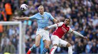 Striker Man City, Erling Haaland (kiri), berduel dengan Gabriel Magalhaes pada pertandingan Liga Inggris pekan 30 di Etihad Stadium, Minggu (31/3/2024) malam WIB. (AP Photo/Dave Thompson)
