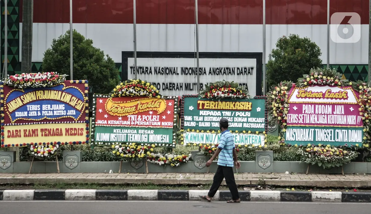 Pejalan kaki melintas dekat karangan bunga yang dipajang di depan Markas Kodam Jaya, Jakarta, Senin (23/11/2020). Ratusan karangan bunga dikirim masyarakat sebagai bentuk dukungan terhadap TNI dan Polri atas tindakan tegas kepada pelanggar protokol kesehtan Covid-19. (merdeka.com/Iqbal S Nugroho)