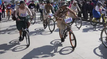 Dengan mengenakan rok panjang dan lebarnya, para pembalap wanita Bolivia ini tanpa kesulitan menggowes sepedanya. (AP Photo/Juan Karita)