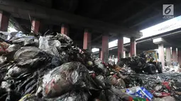 Petugas PPSU menggunakan alat berat mengangkut sampah di kolong Tol Wiyoto-Wiyono, Sungai Bambu, Jakarta, Selasa (15/1). Dalam sehari petugas kebersihan mengangkut sampah hingga 10 truk dengan berat total sekitar 100 ton. (Merdeka.com/Iqbal S. Nugroho)