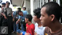 Petugas berbincang dengan warga yang diduga bandar narkoba dan terlibat pengeroyokan di kampung Berlan, Jakarta, Kamis (21/1). Aparat gabungan lakukan penggeledahan dan mencari pelaku tersangka pengeroyokan di kampung Berlan. (Liputan6.com/Yoppy Renato)