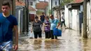 Sejumlah warga melewati jalanan yang banjir akibat hujan deras di Ibu Kota Skopje, Makedonia, Minggu (7/8). Pemerintah menyatakan keadaan darurat sehari setelah setidaknya 21 orang tewas dalam banjir bandang yang disebabkan badai. (Robert ATANASOVSKI/AFP)